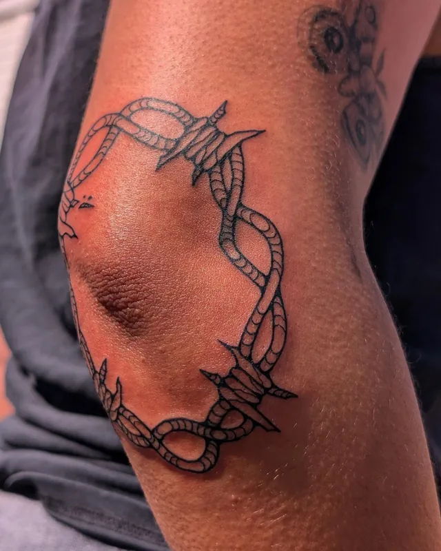 Barbed-wire ring tattoo around an elbow