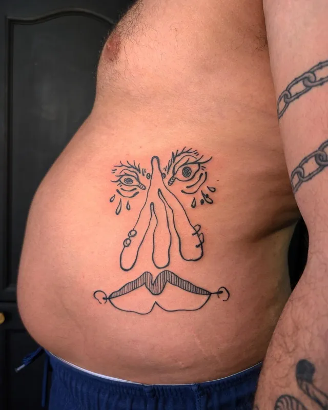 Playful linework face tattoo on a belly